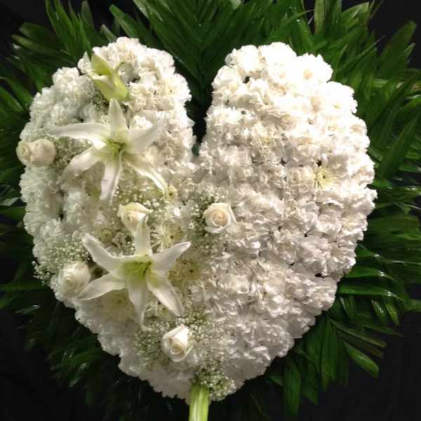 White heart-shaped funeral wreath with lilies and roses