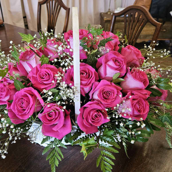 Basket of bright pink roses with baby's breath and greenery
