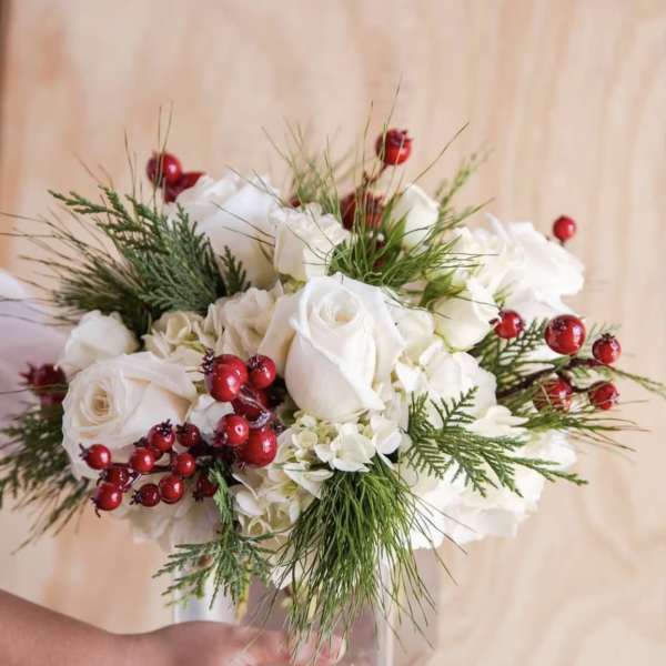 White rose bouquet with red berries in a clear vase
