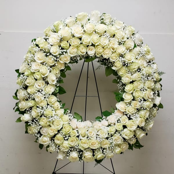 Large white rose wreath on a black stand