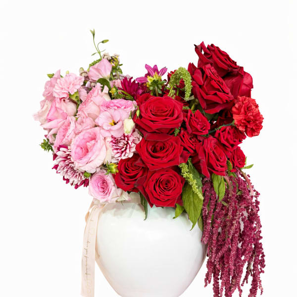 Pink and red floral arrangement in a white vase