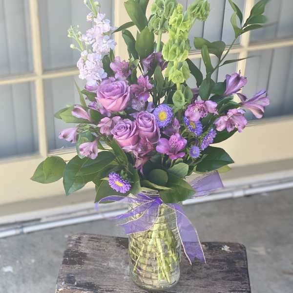 Mixed purple bouquet in a glass vase with a ribbon