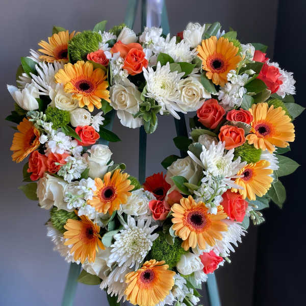 Heart-shaped floral wreath with orange gerbera daisies, white roses, and white mums