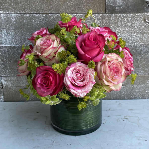 Pink and cream roses arranged in a green round vase