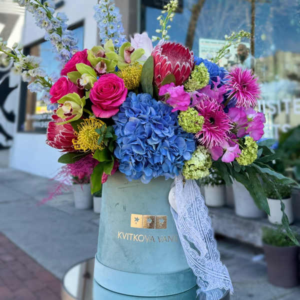 Colorful bouquet in a blue hatbox with lace ribbon