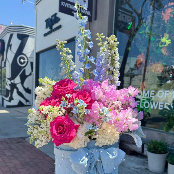 Bouquet of pink roses and pastel flowers in a blue hatbox with a bow