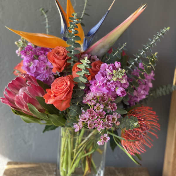 Tropical bouquet with orange birds of paradise and pink roses in a glass vase