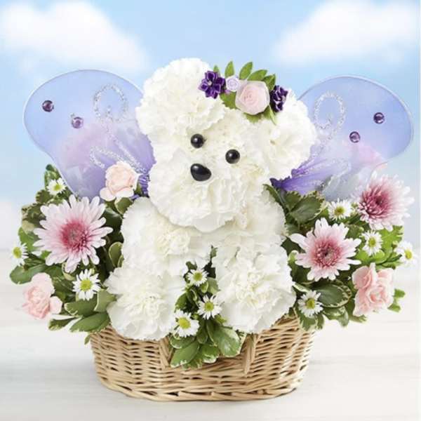 White teddy bear in a wicker basket surrounded by pink and purple flowers