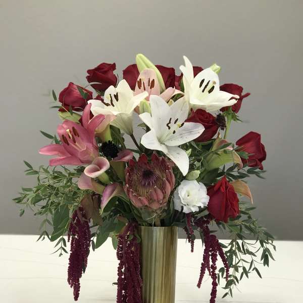 Bouquet of red roses, white lilies, and pink calla lilies in a gold vase