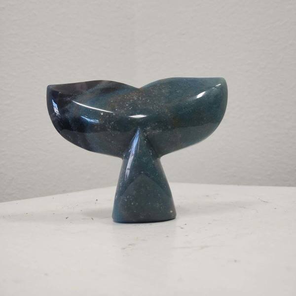 Dark blue whale tail sculpture on a white surface
