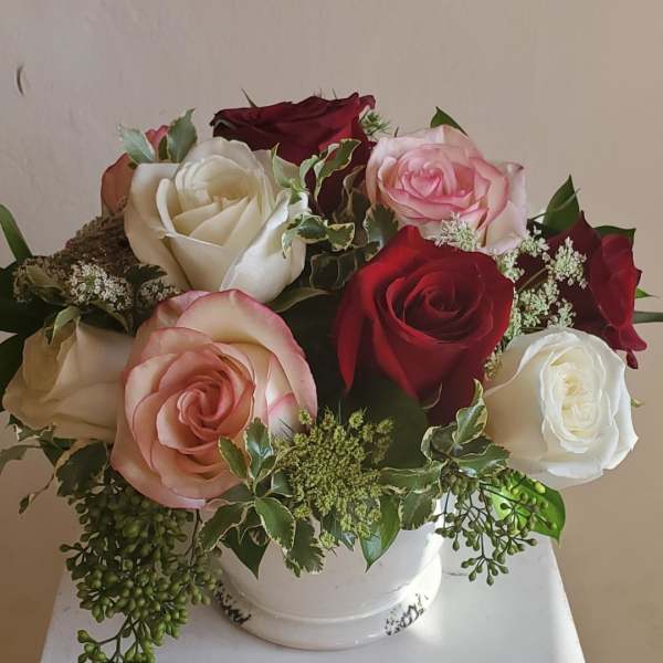Bouquet of red, white, and pink roses in a white vase