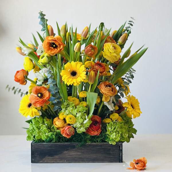Mixed orange and yellow flowers in a dark wooden box