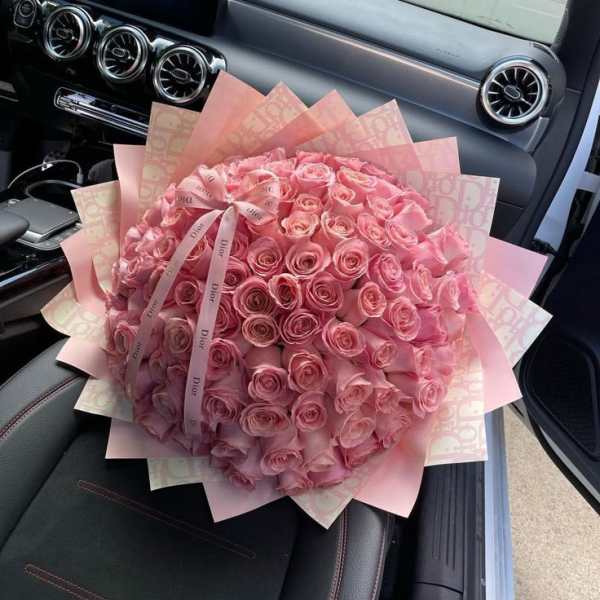 Large bouquet of pink roses wrapped in pink paper with a ribbon