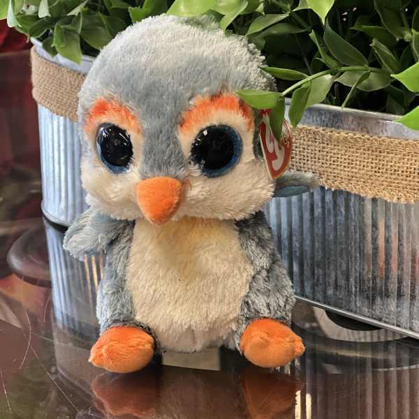 Plush penguin toy in front of potted greenery