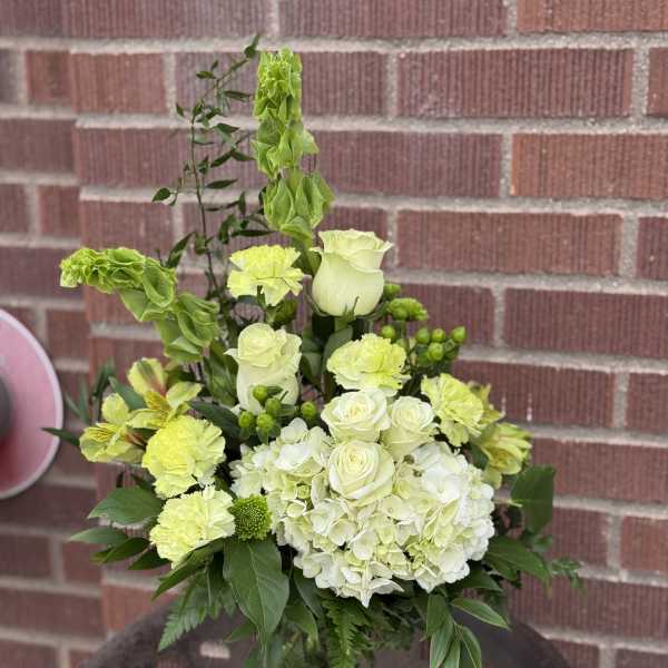 White and lime-green floral arrangement in a glass vase