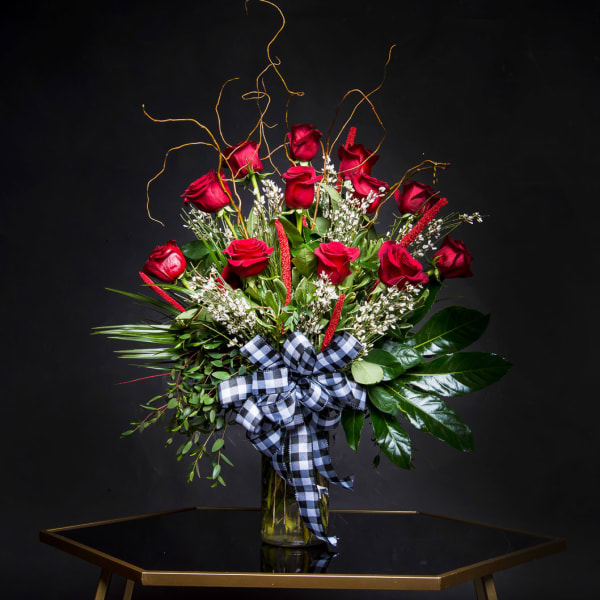 Red roses in a glass vase with a black-and-white ribbon