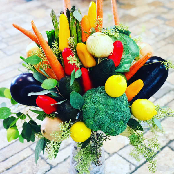 Vegetable bouquet with carrots, peppers, broccoli, onions, and greens in a vase