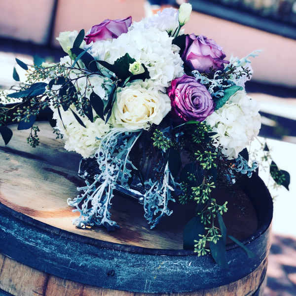 Bouquet of white and purple roses with white hydrangeas in a glass vase