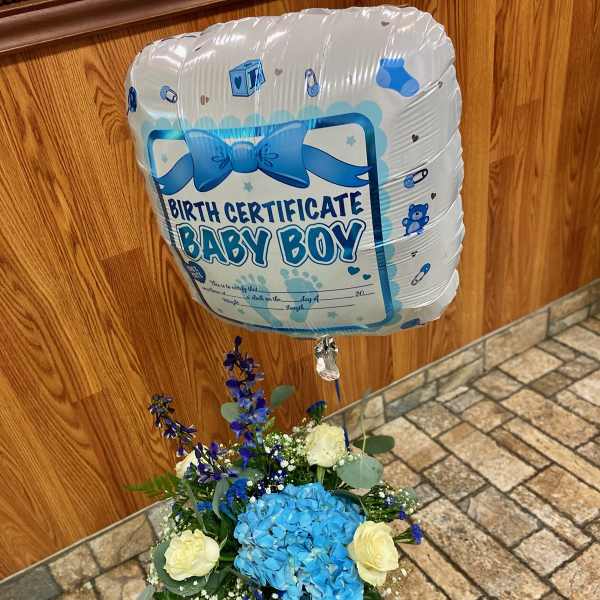 Blue baby boy balloon above a blue and white flower arrangement