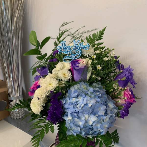 Blue hydrangea bouquet with purple and white flowers in a purple vase