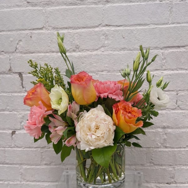 Mixed bouquet of pink, orange, and white flowers in a glass vase