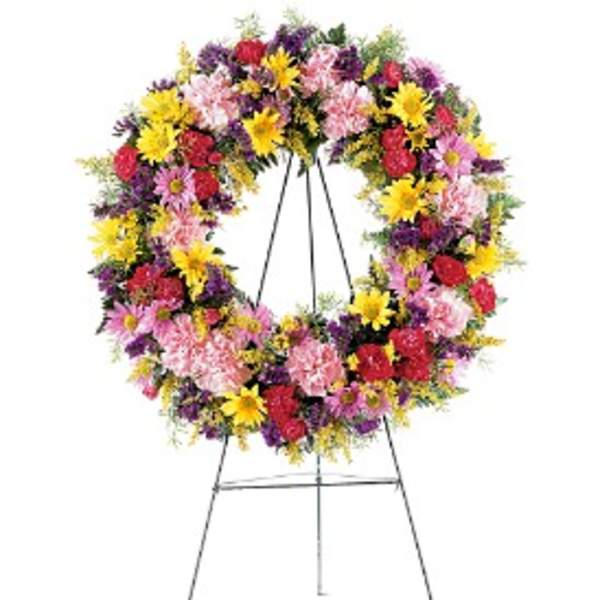 Colorful standing wreath of yellow, pink, red, and purple flowers on a metal easel