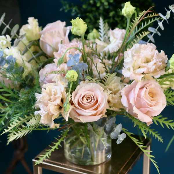 Blush roses and pale flowers in a clear glass vase