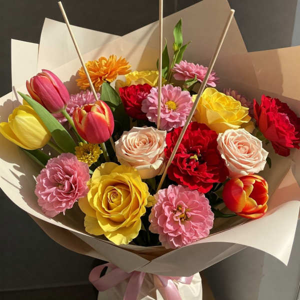 Bouquet of colorful tulips, roses, and daisies wrapped in paper
