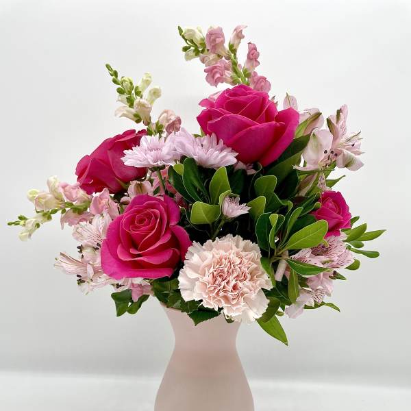 Pink roses and pale flowers arranged in a blush vase