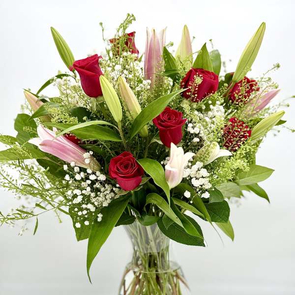 Red roses and pink lilies in a clear glass vase