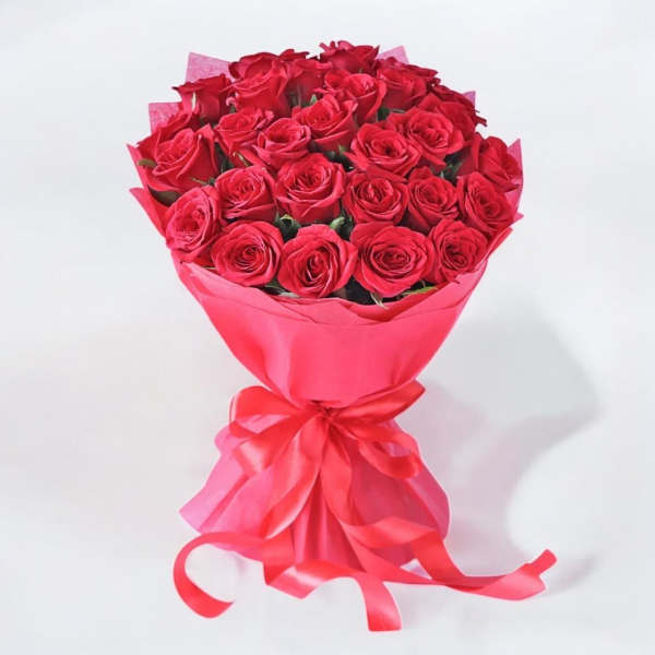 Bouquet of red roses wrapped in pink paper with a ribbon