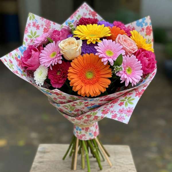 Colorful bouquet of gerbera daisies, roses, and carnations in floral wrap