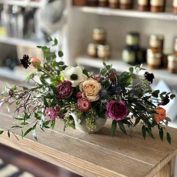 Low floral arrangement with roses and anemone in a white vase