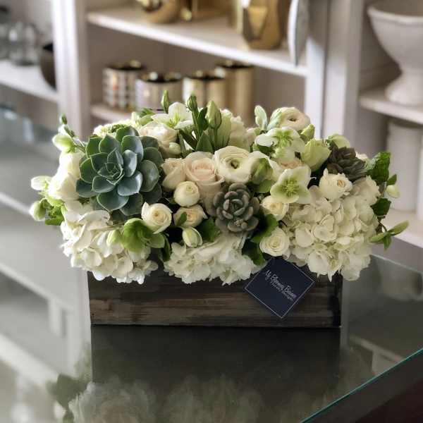 White floral arrangement with succulents in a wooden box