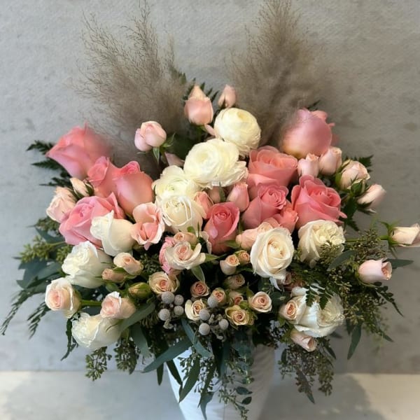 Pink and white roses arranged in a white vase