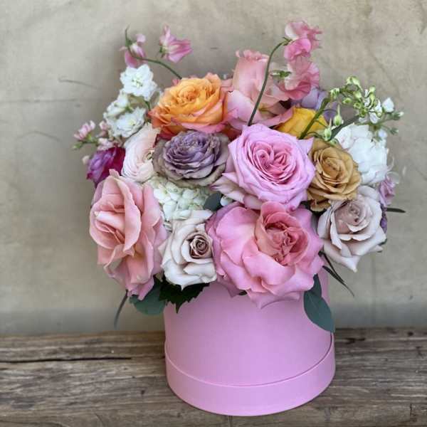 Pink and peach roses arranged in a round pink box