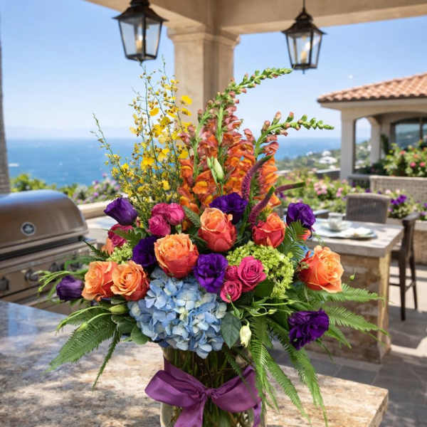 Colorful mixed flower arrangement in a glass vase with a purple ribbon