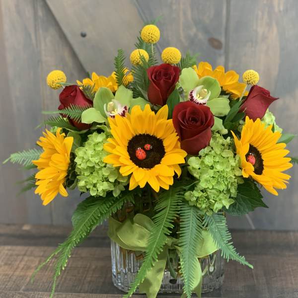 Bouquet of sunflowers and red roses in a glass vase