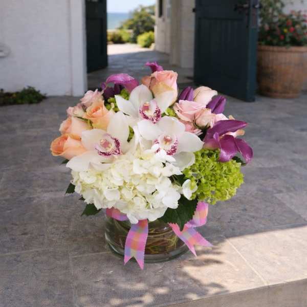 Bouquet of white orchids, pink roses, and green hydrangea in a glass vase