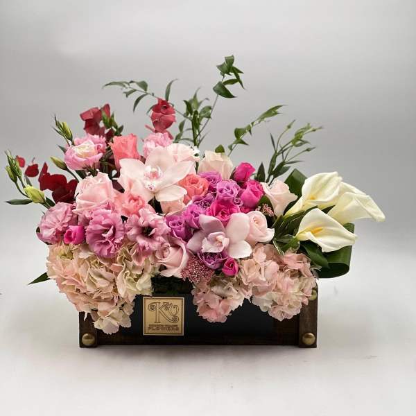 Pink and white floral arrangement in a dark wooden box