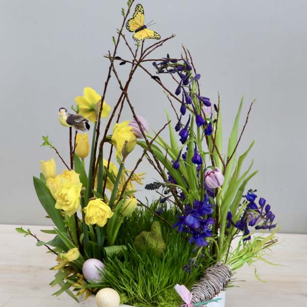 Spring floral arrangement with yellow and purple blooms in a white container