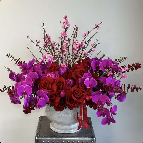 Red roses and purple orchids in a white vase with pink blossoms