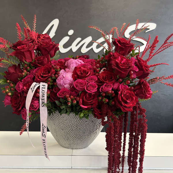 Large red rose arrangement in a silver textured vase with pink ribbon