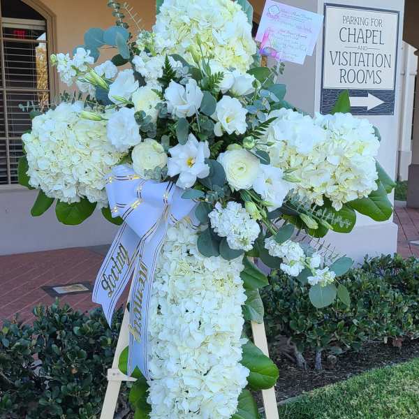 White funeral standing spray on an easel with a ribbon