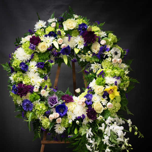 Large floral wreath on an easel with white, purple, and green flowers