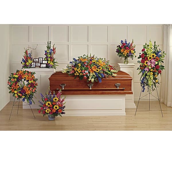 Colorful funeral casket spray with standing floral tributes