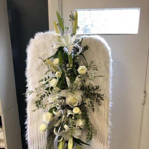 White floral standing spray on an easel with lilies and roses