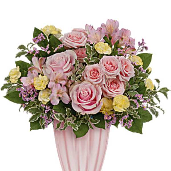 Pink and yellow bouquet of roses and mixed flowers in a pink glass vase