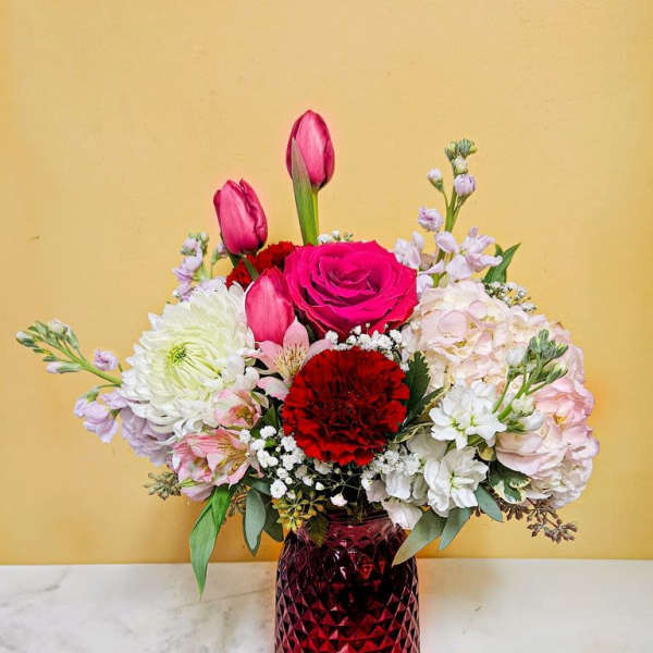 Mixed bouquet of pink and white flowers in a red glass vase