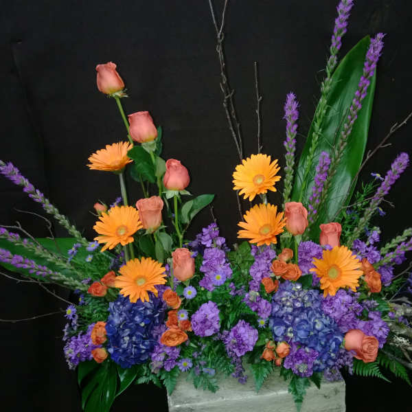 Colorful floral arrangement with orange daisies, pink roses, and purple blooms